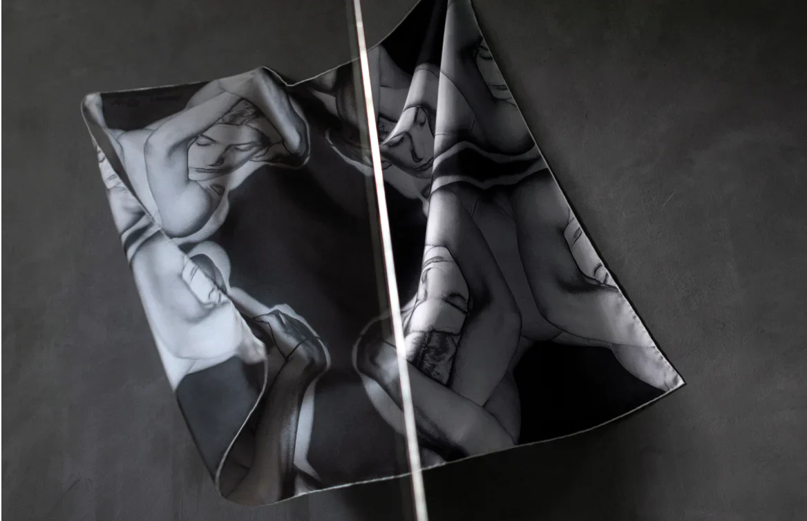 A Man Ray scarf in black and white with an abstract image of a woman pictured on a dark background with a single shaft of bright light cutting across it.