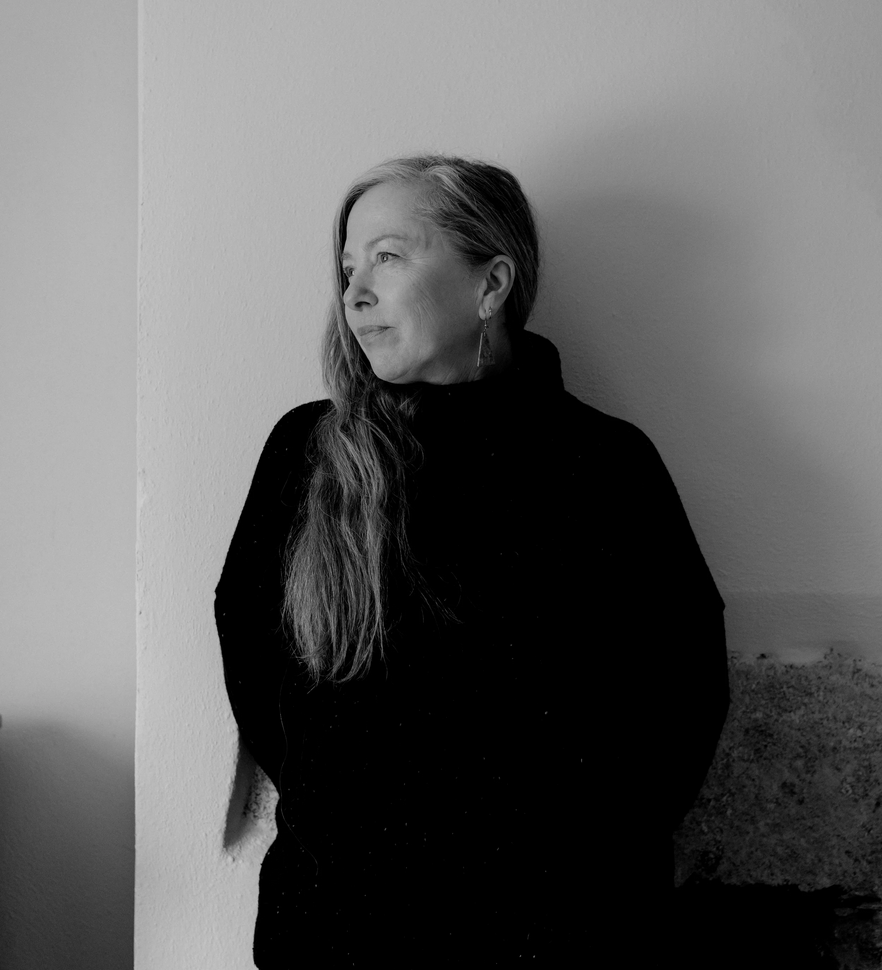 Black and white portrait of artist Dot Wade leaning against a wall.