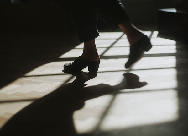 Silhouette of a person's legs with shoes on a floor with shadows