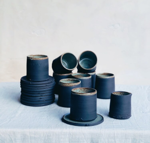 Artfully stacked black hand thrown plates and cups by Alex Gabriel