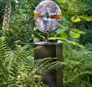 torus shaped marble sculpture mouted atop a wooden post in the lush garden at Withiel