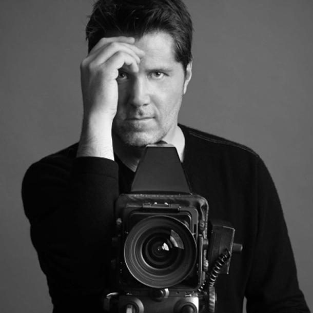 black and white photo of James T Murray shading his eys with a hand and looking over a medium format camera