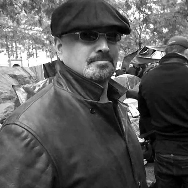 photo of artist and writer Ross Klavin wearing a beret and leather jacket standing in a park
