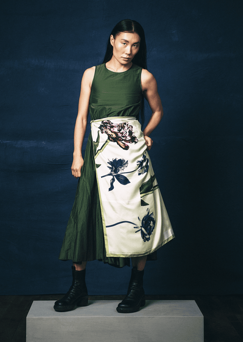 Person wearing a green top and floral scarf by James T Murray as a skirt against a dark background