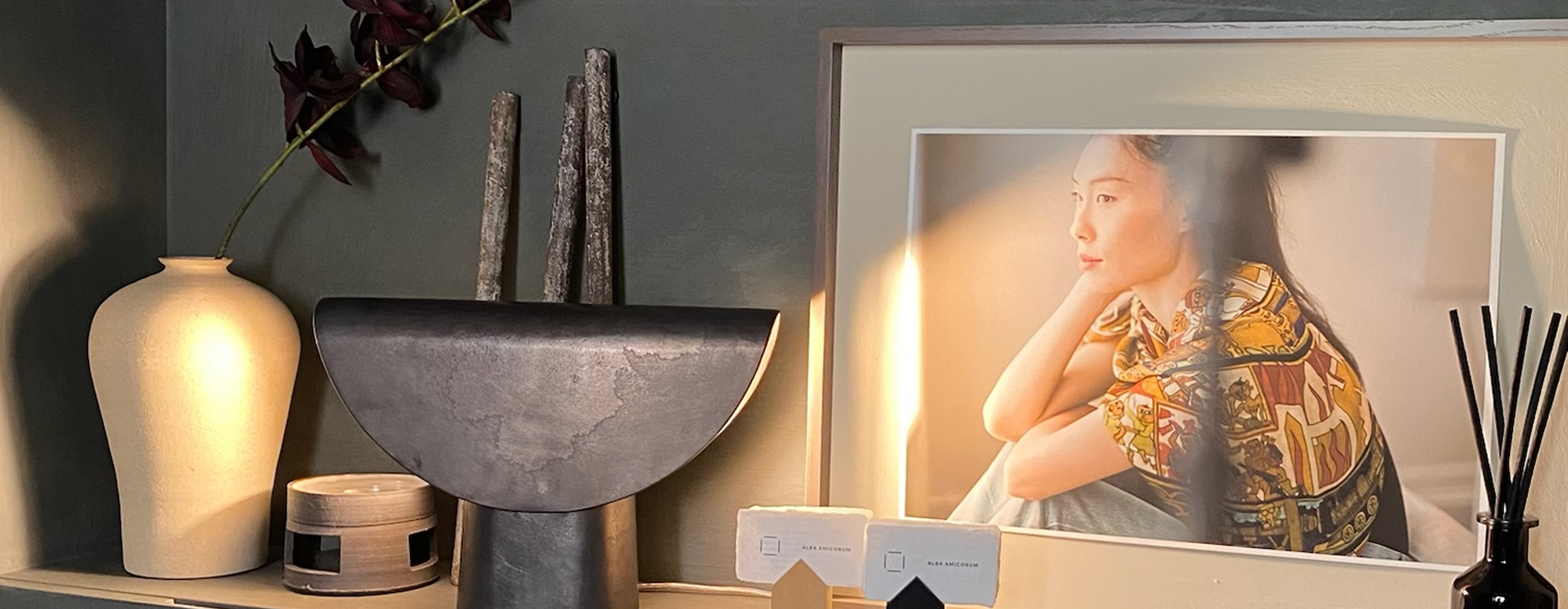 Decorative sideboard at Atelier Alba Amicorum with a vase, sculpture, and framed photo on a shelf.