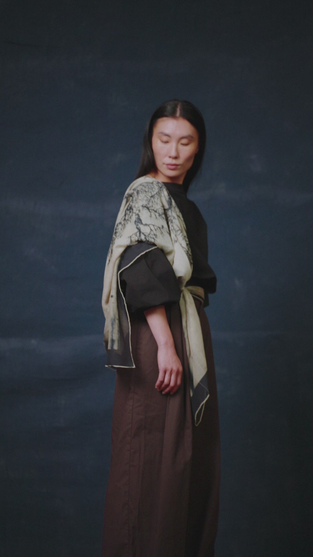 video of a Person wearing a black outfit with a James T Murray patterned scarf against a dark blue background